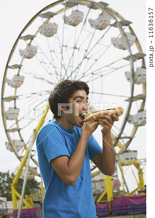 Mixed Race teenaged boy eating hot dog at carnival Mixed Race teenaged boy eating hot dog at carnival 11636157