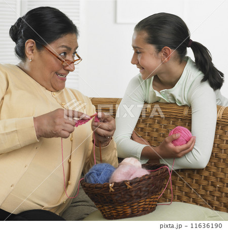 Hispanic grandmother and granddaughter with knitting supplies 11636190