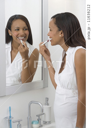 Pregnant African woman applying lipstick in mirror 11636212