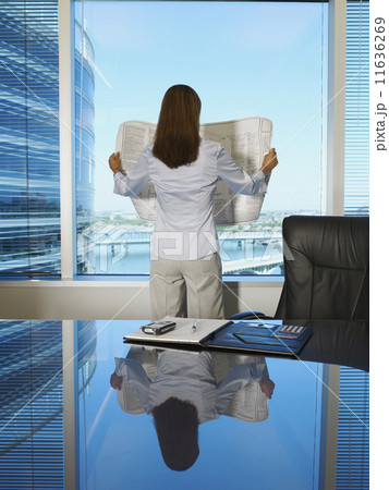 Hispanic businesswoman reading blueprint 11636269