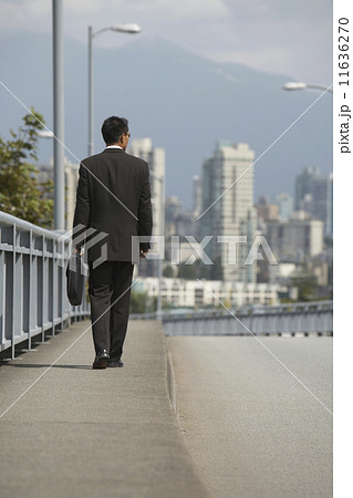 Asian businessman walking on urban bridge 11636270