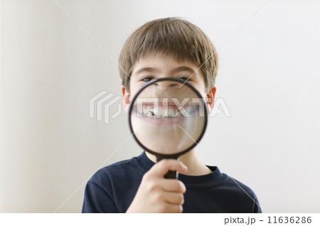 Portrait of boy smiling through magnifying glass 11636286