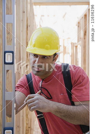 Mixed Race male construction worker using level 11636296