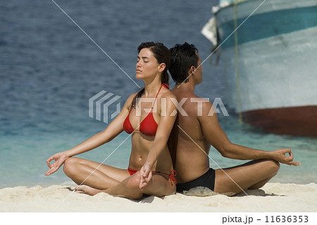 Multi-ethnic couple meditating at beach 11636353