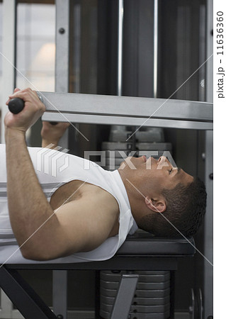 Hispanic man using weight machine 11636360