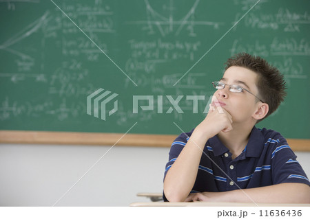 Hispanic boy thinking at school desk 11636436