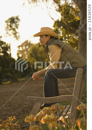 Asian woman sitting on park bench 11636529
