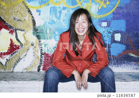 Portrait of a young woman sitting in front of a graffiti wall 11636587