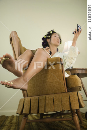 Asian woman in curlers looking in mirror 11636656
