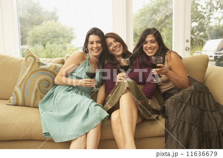 Portrait of three women sitting on couch with wine glasses 11636679