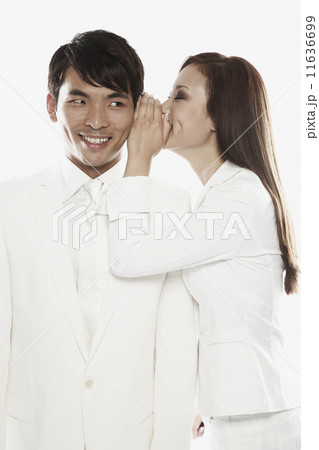 Asian woman telling secret to co-worker 11636699