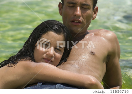Hispanic couple laying on rock in water 11636716
