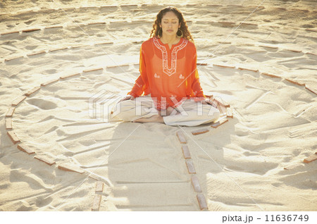 Woman sitting cross-legged in the middle of a meditation labyrinth 11636749