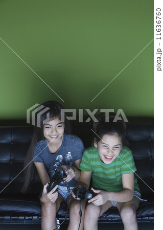 Two girls playing video game on sofa 11636760