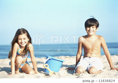 Brother and sister play in the sand at the beach 11636824