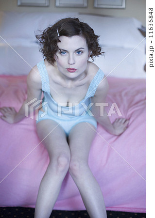 Woman leaning forward on bed in camisole and panties Woman leaning forward on bed in camisole and panties 11636848