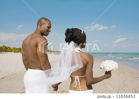 African bride and groom holding hands at beach 11636852