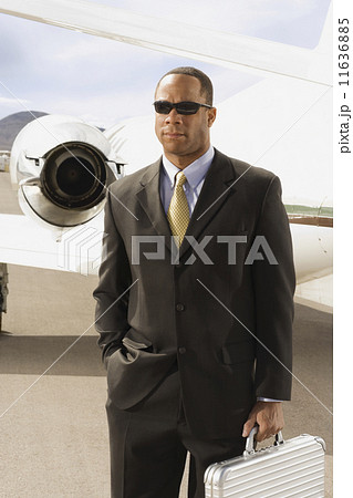 African American businessman in front of airplane African American businessman in front of airplane 11636885
