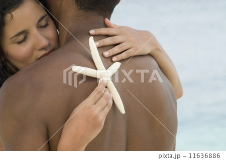 Hispanic couple hugging with starfish Hispanic couple hugging with starfish 11636886