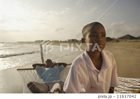 African father and son in hammock at beach 11637042