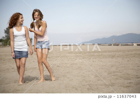 Two teenage girls walking on beach 11637043