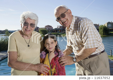 Hispanic grandparents and granddaughter next to swimming pool 11637052