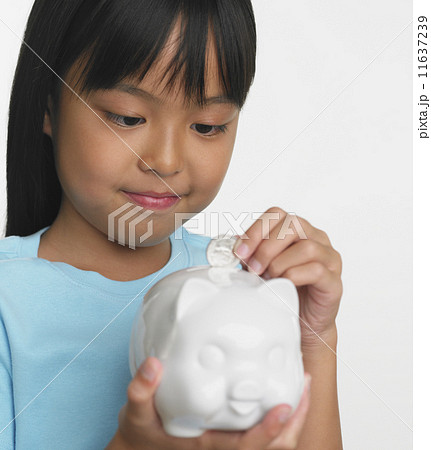Young Asian girl putting coin in piggybank 11637239