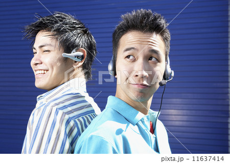 Two young men back to back wearing headsets 11637414