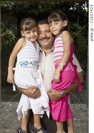 Hispanic father hugging daughters 11637423