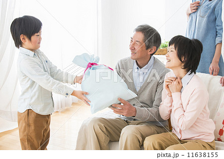 祖父母にプレゼントを渡す孫 11638155