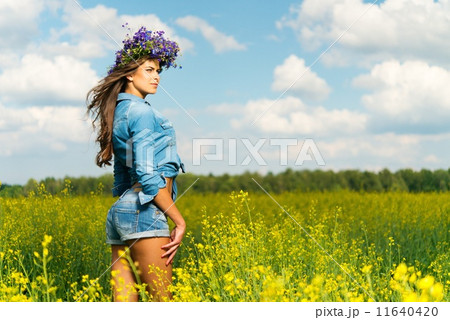 Beautiful young brunette in shorts and chaplet in a yellow field 11640420