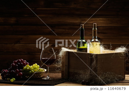 Bottles of red and white wine, glass and grape on a wooden interior 11640679