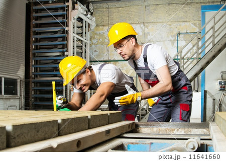 Worker and foreman in a safety hats performing quality check on a factory 11641660