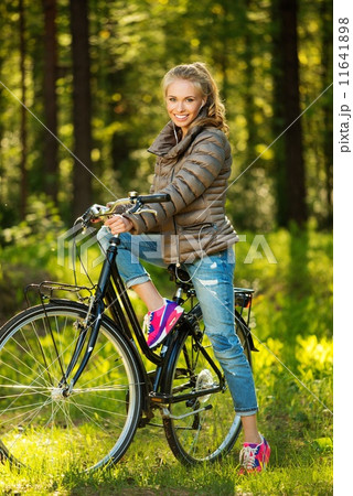 Cheerful teenage girl listens music on a bicycle outdoors 11641898