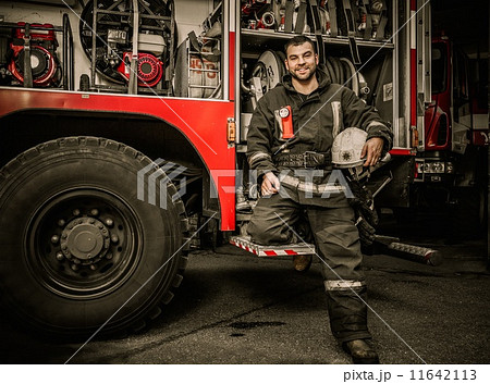 Cheerful firefighter near truck with equipment 11642113