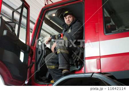 Fireman behind steering wheel of a firefighting truck 11642114