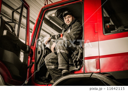 Fireman behind steering wheel of a firefighting truck Fireman behind steering wheel of a firefighting truck 11642115