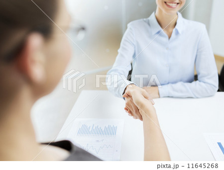two smiling businesswoman shaking hands in office two smiling businesswoman shaking hands in office 11645268