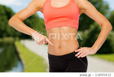 close up of woman pointing finger at her six pack close up of woman pointing finger at her six pack 11645412