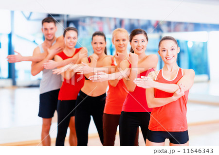 group of smiling people stretching in the gym group of smiling people stretching in the gym 11646343