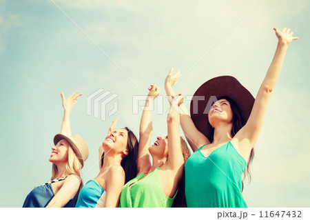 smiling girls with hands up on the beach 11647432