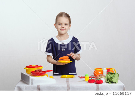 Girl with a plate of carrots on toy kitchen 11669117