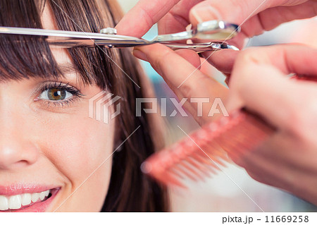 Hairdresser cutting woman bangs hair in shop 11669258