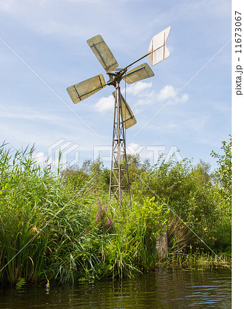 Small and rusted old metal windmill at the waterside Small and rusted old metal windmill at the waterside 11673067
