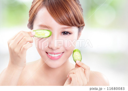 beautiful woman holding cucumber slices on face 11680083