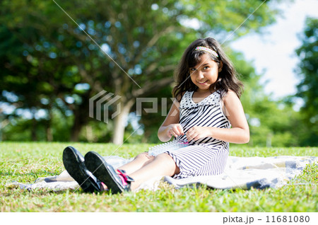 Young asian girl happily playing on the picnic mat in the park 11681080