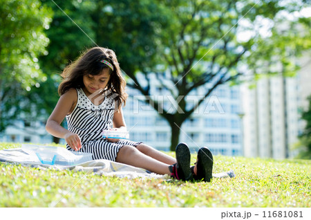 Young asian girl happily playing on the picnic mat in the park 11681081
