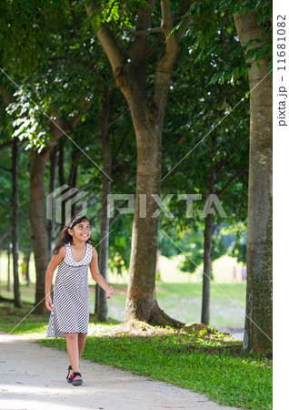 Smiling young asian girl happily walking and hopping in the park Smiling young asian girl happily walking and hopping in the park 11681082