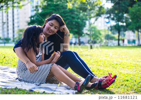 Young Indian Mother and daughter chatting on the picnic mat in the park Young Indian Mother and daughter chatting on the picnic mat in the park 11681121