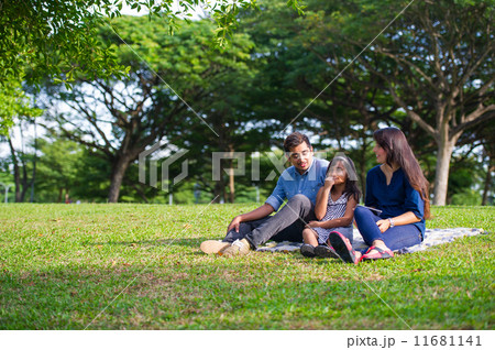 A young asian family having a good time on a picnic mat in the park 11681141